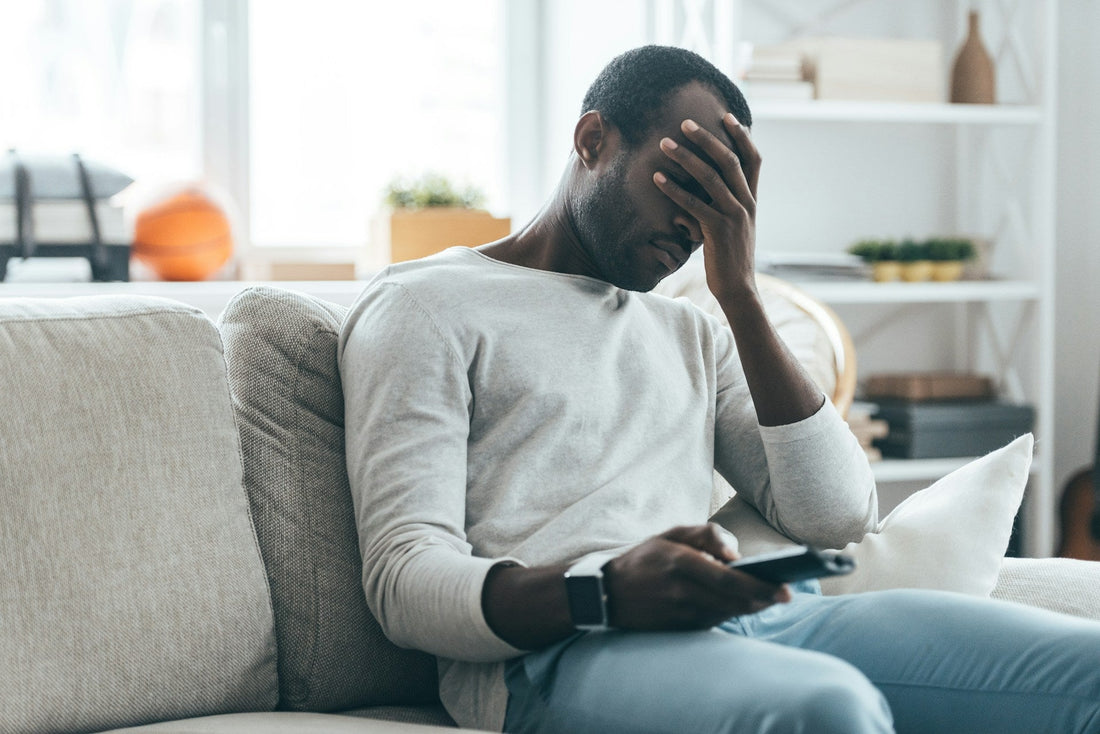african american man confused on How to Know If heShould Break Up or not. phone in hand holding his head