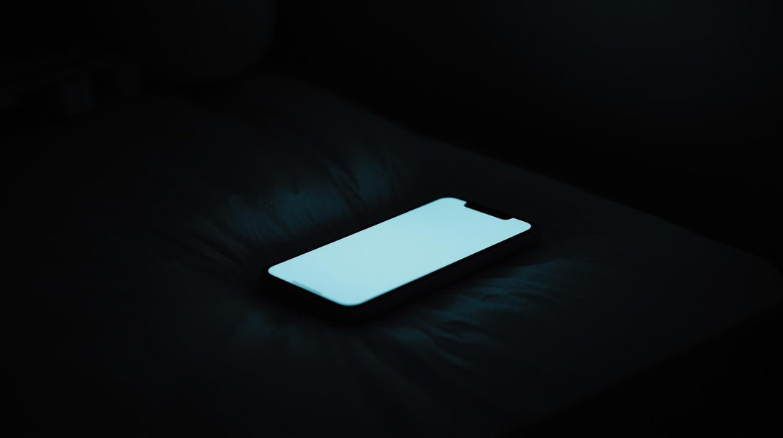 Phone screen lighting up in a dark room, symbolizing anticipation, anxiety, and waiting for contact after a breakup.
