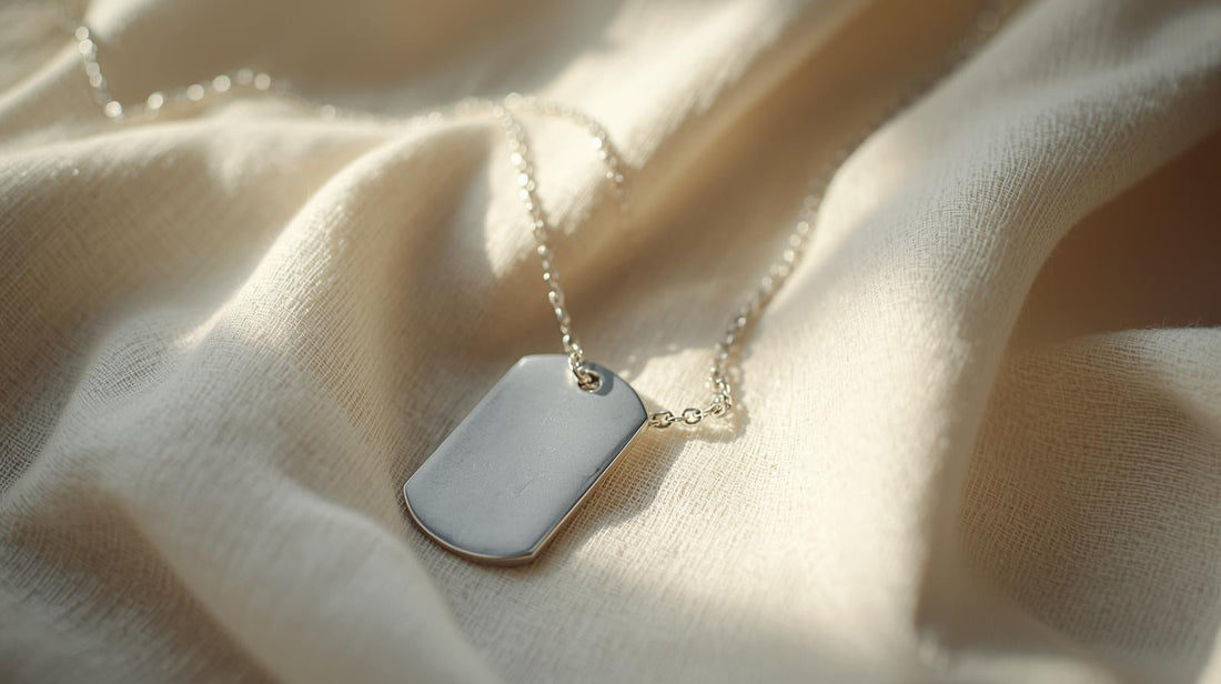 Silver dog tag necklace resting on soft creamy linen in natural light, symbolizing personal identity and lingering emotional attachment after a breakup.