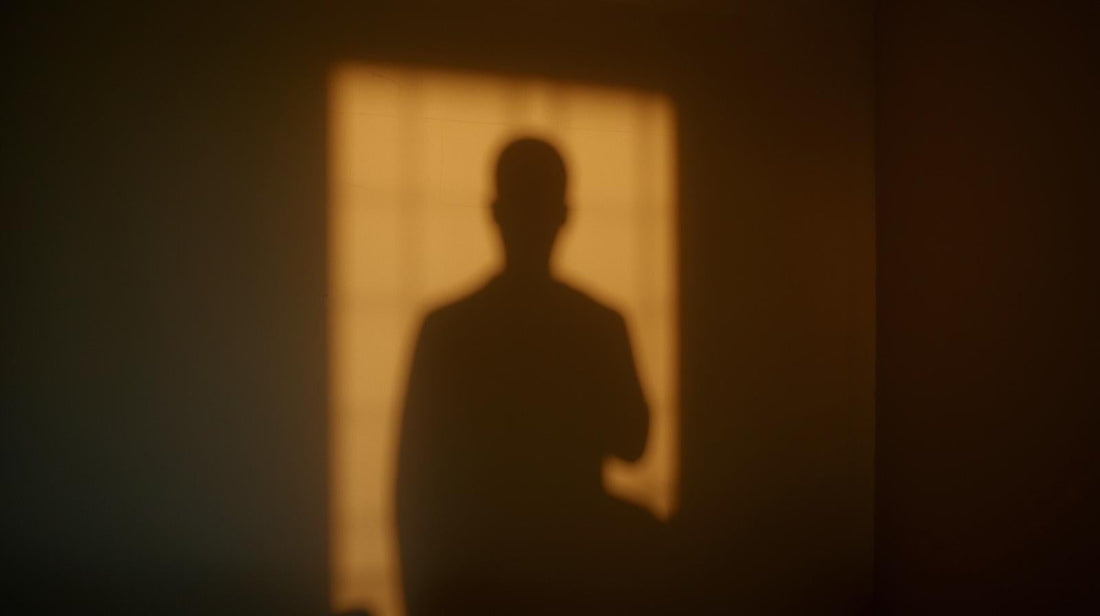 Shadow of a single person on a wall in warm late afternoon light, symbolizing solitude and emotional introspection after a breakup.