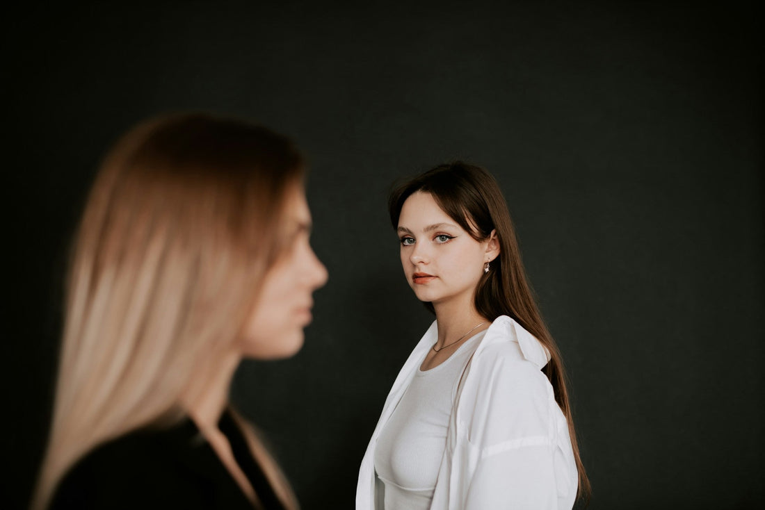 Woman looking toward another woman in the foreground, representing jealousy, comparison, and insecurity after a breakup.