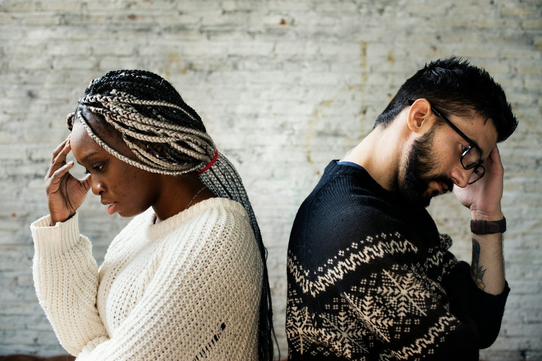 Couple sitting back to back and looking stressed, representing partner-like closeness without clear commitment