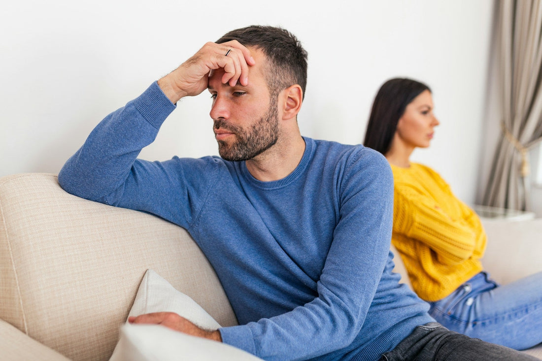 Distant couple sitting apart after conflict, symbolizing avoidant communication and emotional withdrawal.