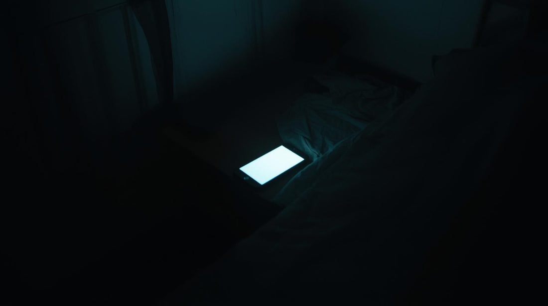 Smartphone glowing in a dark bedroom symbolizing social media-triggered jealousy after a breakup