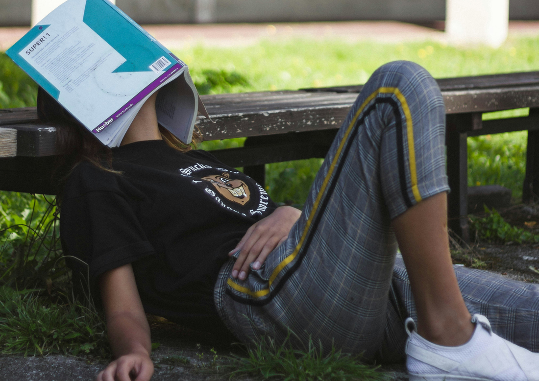 woman lying down with book covering her face depicting ldr burnout