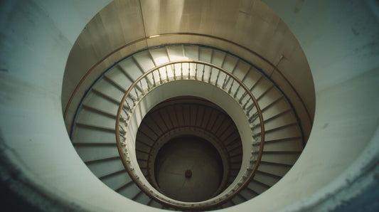 Circular staircase viewed from above in soft natural light, symbolizing repetitive thought patterns and emotional loops