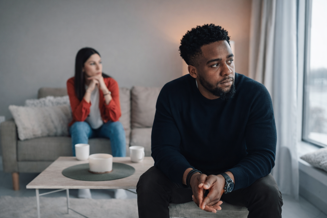 Couple sitting apart in a living room after a breakup, showing emotional distance and unresolved tension between partners