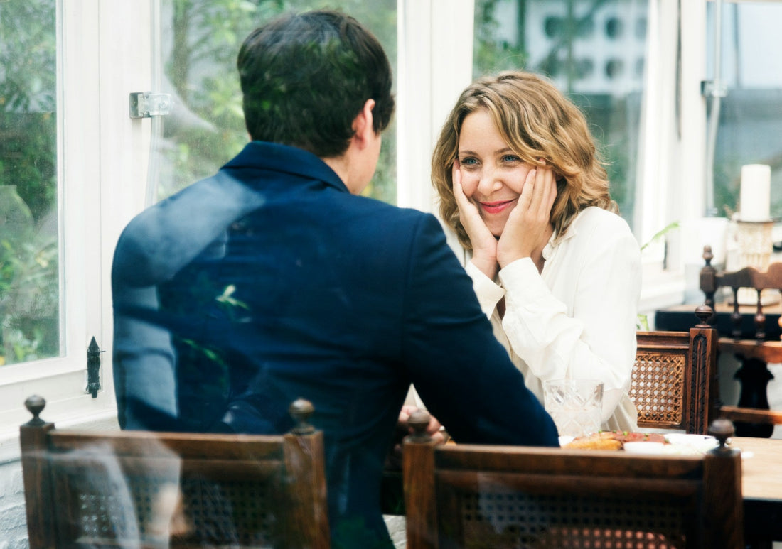 Mature woman smiling across the table from a man on a date, representing dating after 50, new relationships and starting over with confidence.