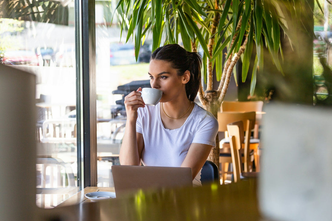 Woman sitting alone in a café with a coffee, reflecting on whether she is dating too soon after a breakup.