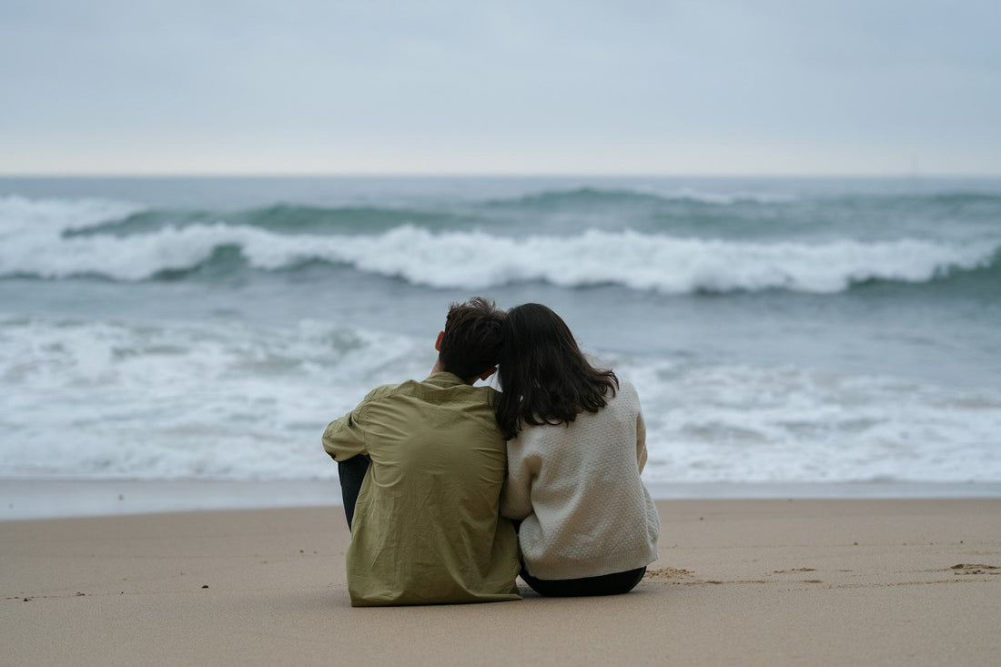 Couple sitting close together on a beach, representing healthy emotional dependence, mutual support, and balanced interdependence in a relationship