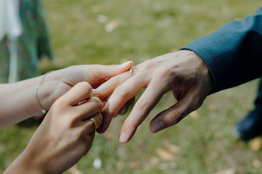Woman placing a promise ring on her boyfriend’s finger, representing promise rings for boyfriends and commitment rings for him
