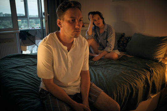 Couple sitting apart in bed while emotional disconnection creates distance and lowers sexual desire in their relationship