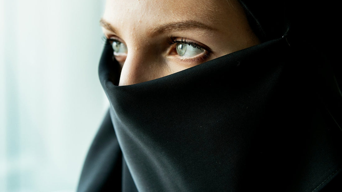 Muslim woman wearing a black niqab looking away thoughtfully, representing emotional pressure and manipulation in a Muslim relationship.