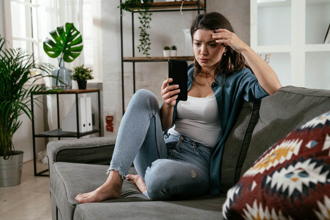 Woman looking concerned at a message on her phone after an ex contacts her while they are with someone else.