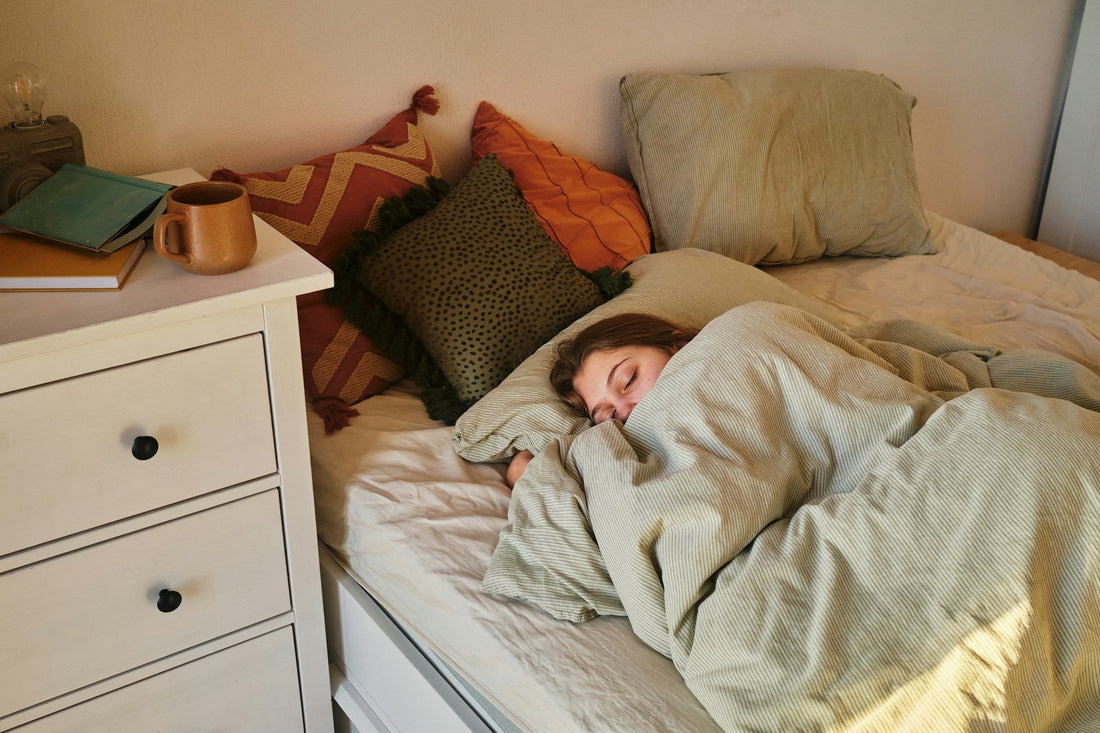 Woman resting in bed under a blanket while coping with fatigue from chronic illness.