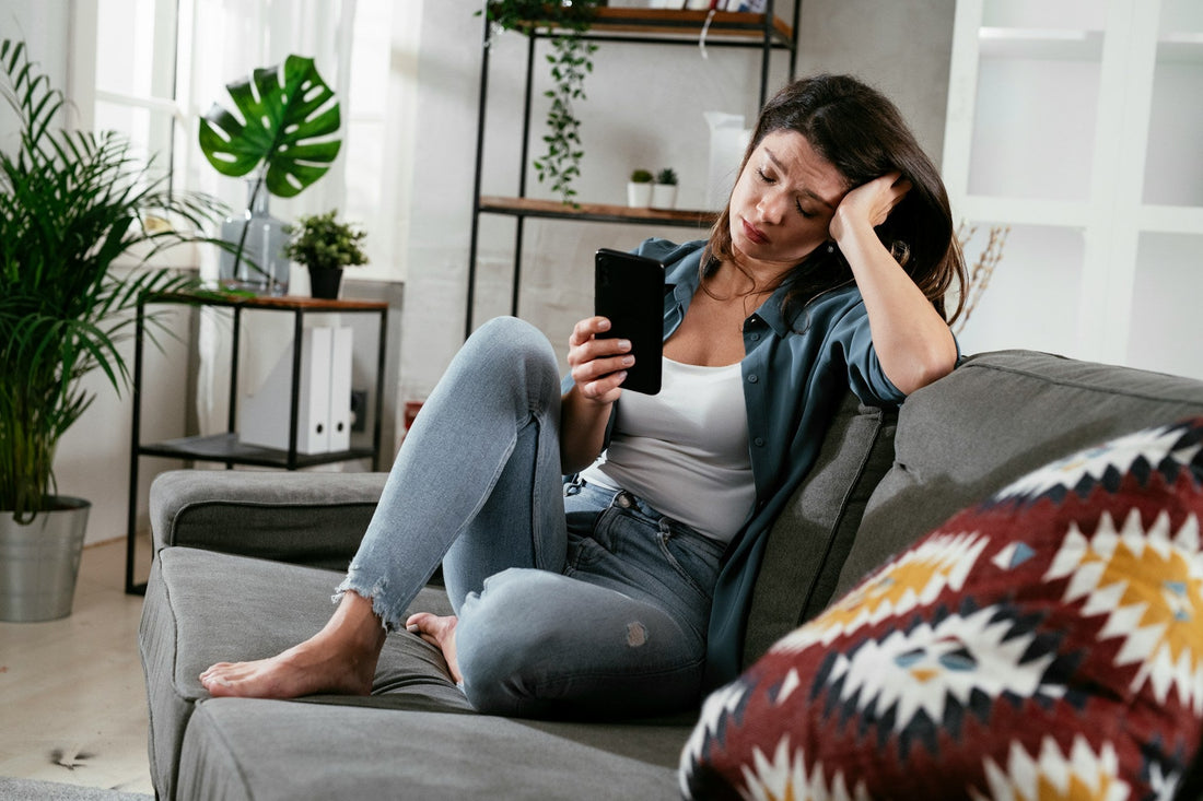 Woman looking upset while checking her phone, representing confusing or emotional contact with an ex after a breakup