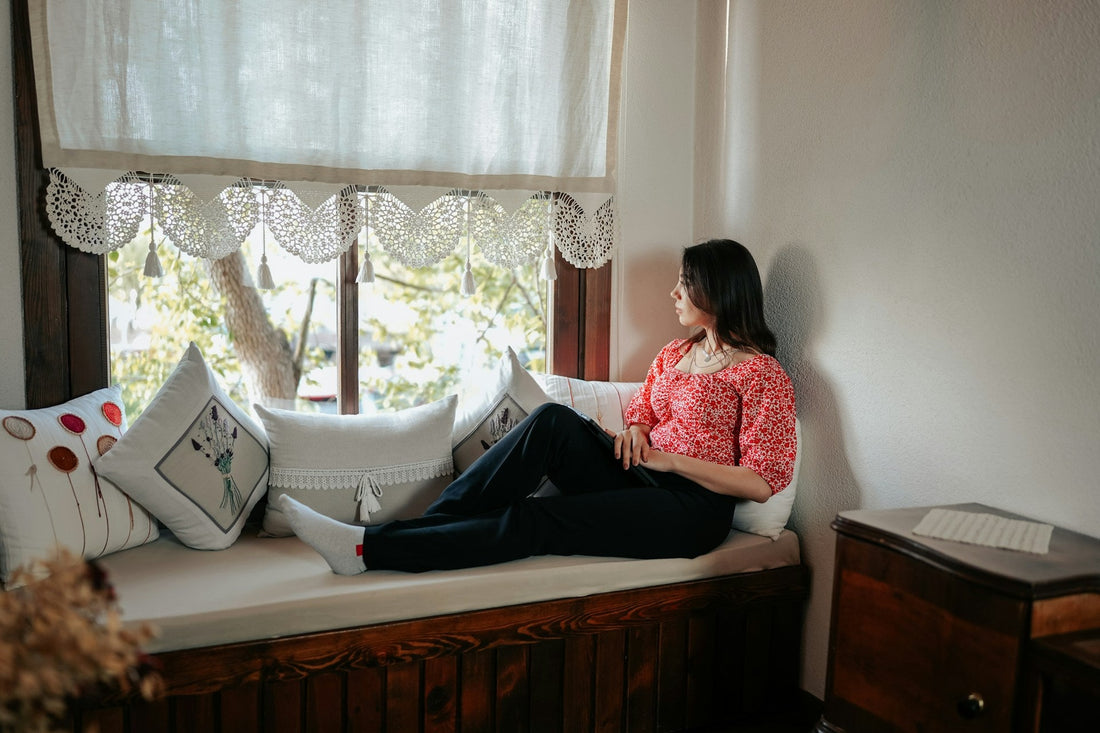 Woman looking out window thinking about breakup recovery and how long it takes to get over an ex