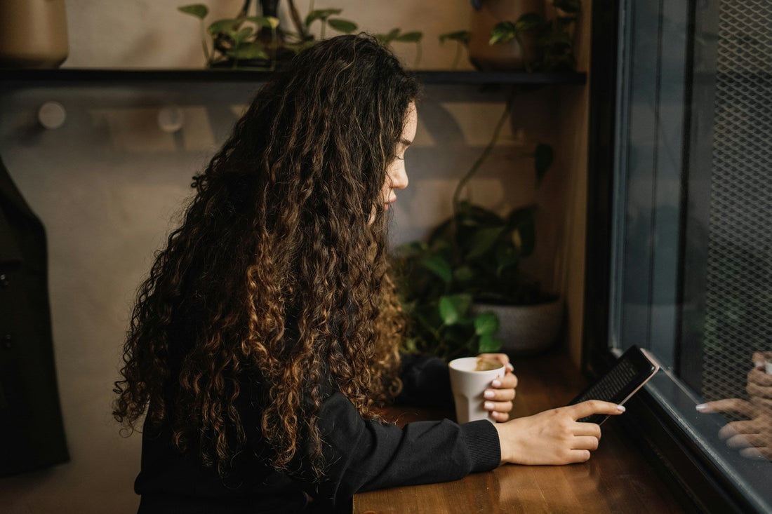 Woman looking at her phone while having coffee, representing texting before meeting someone in person for a first date.