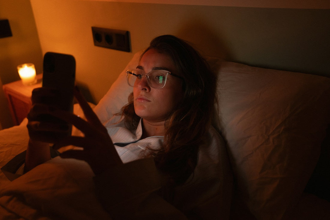 Woman lying in bed at night looking at her phone while waiting for a text reply from someone she is dating.