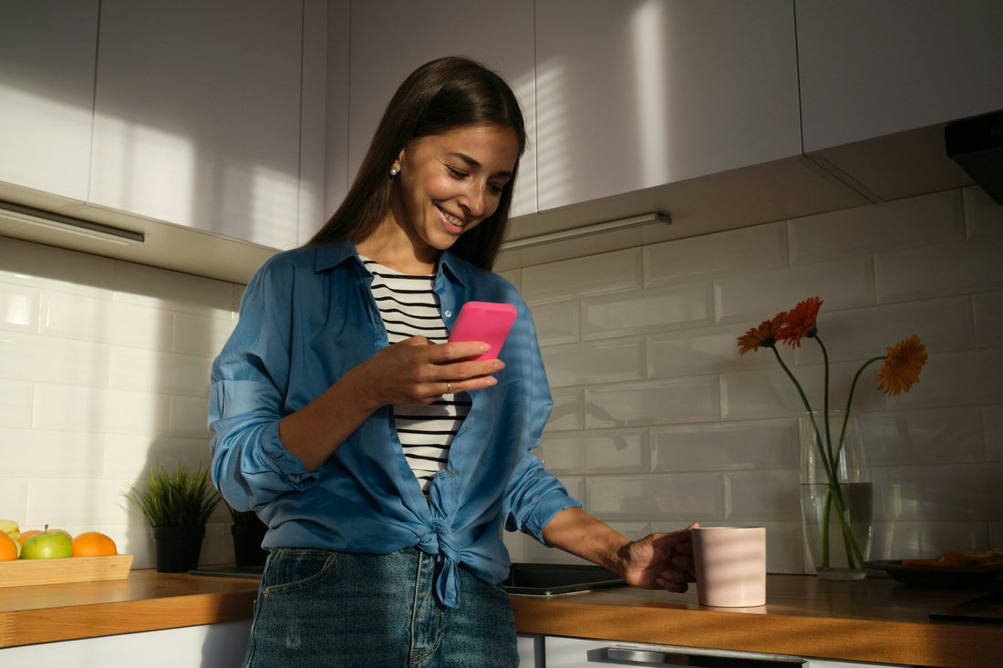 Woman smiling while reading a text message on her phone, representing a relaxed and healthy texting rhythm in early dating.