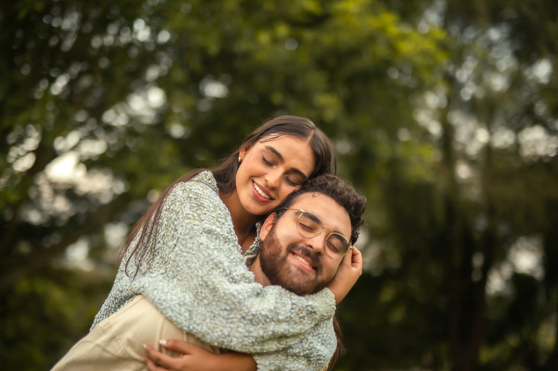 Couple embracing outdoors with relaxed smiles, representing affection, physical closeness and feeling emotionally connected in a relationship.
