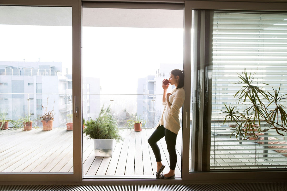 young woman relaxing on balcony with city view holding cup of coffee or tea learning how to be single after a relationship