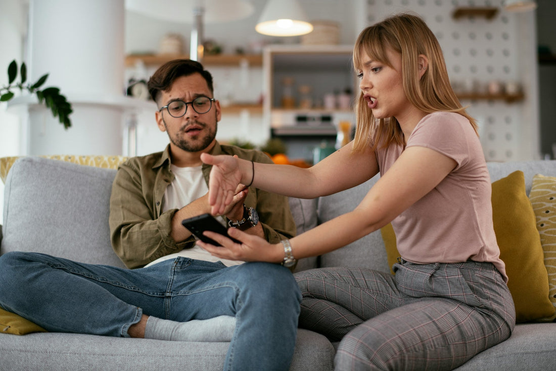 **SEO alt text:** `Woman confronting her boyfriend about suspicious phone activity and possible cheating in their relationship`