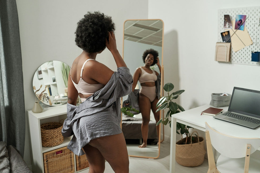 woman looking in mirror concerned about feeling attractive again after a breakup.