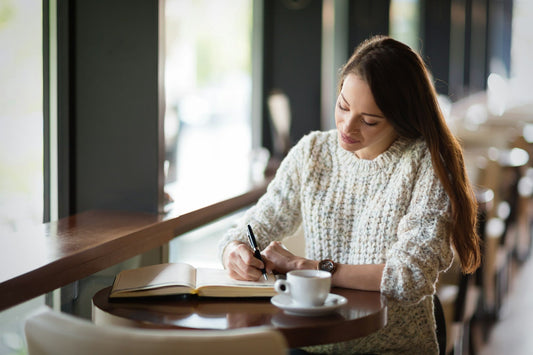 Beautiful young woman sitting in restaurant and writing, trying to find herself again after a relationship