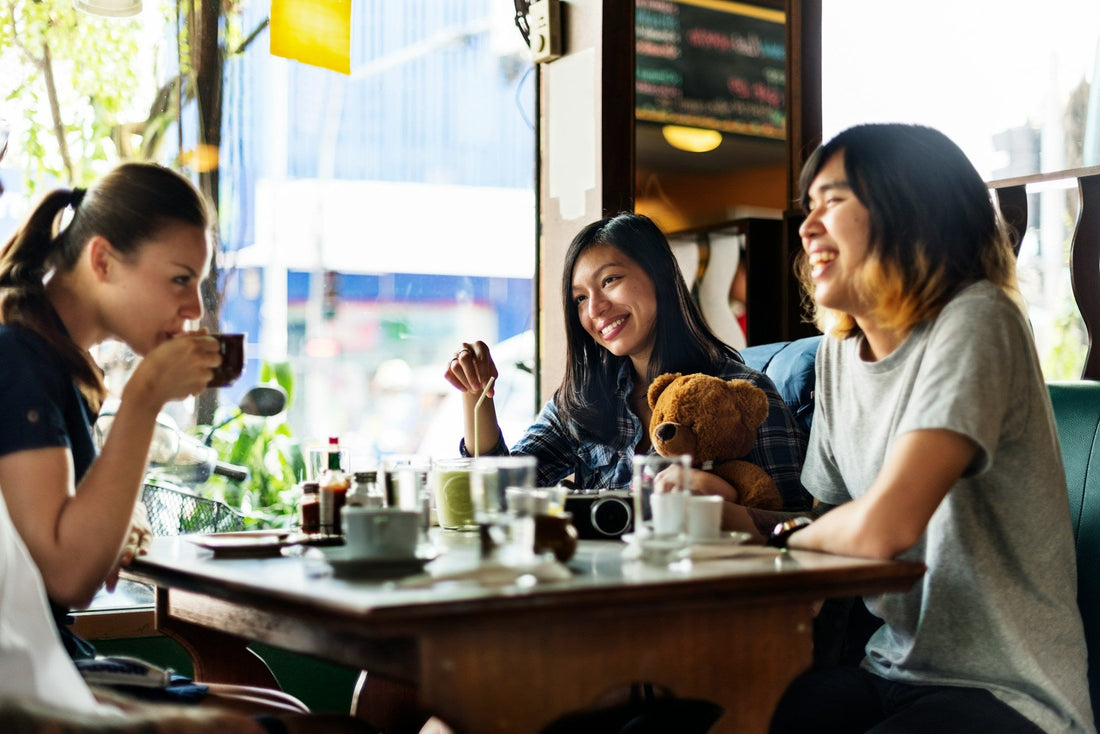 Group Of women Drinking Coffee with a woman amongst them trying to make new friends after a breakup