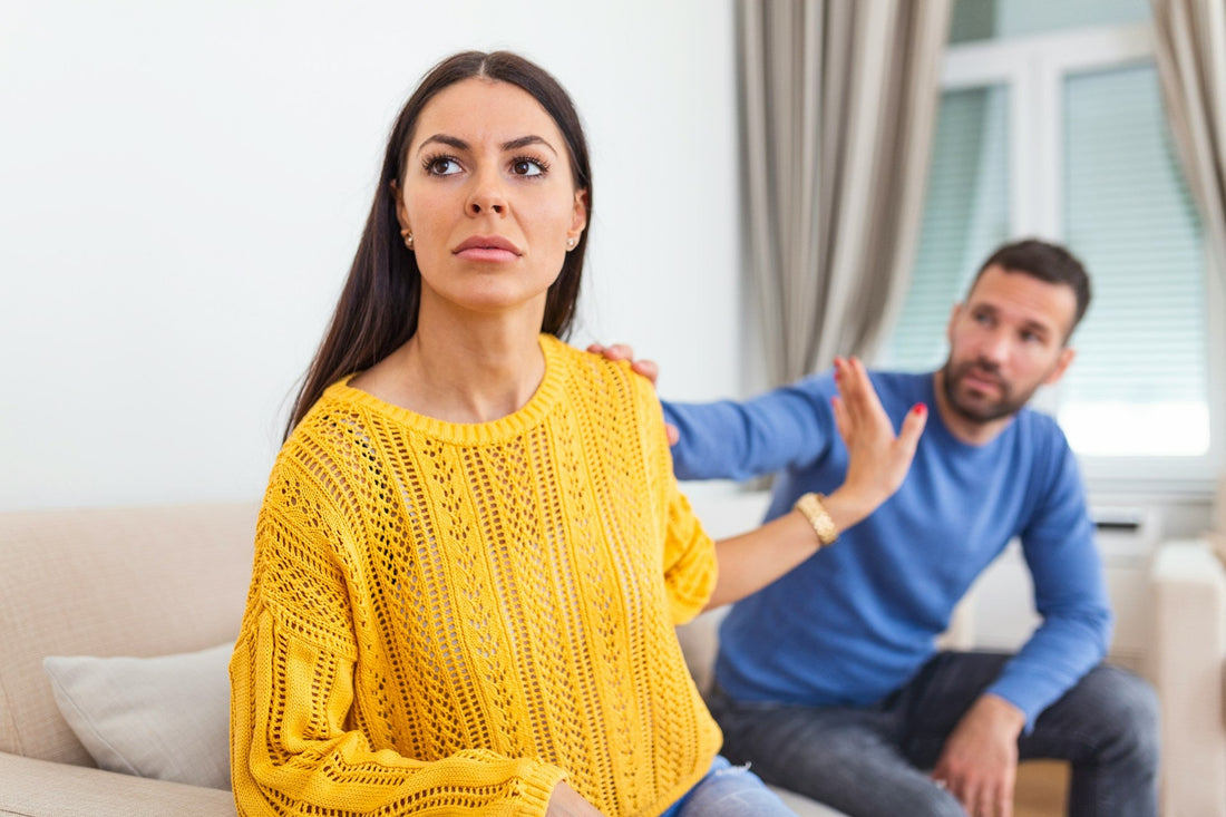 Woman raising her hand to set a firm boundary while her partner reaches toward her after conflict