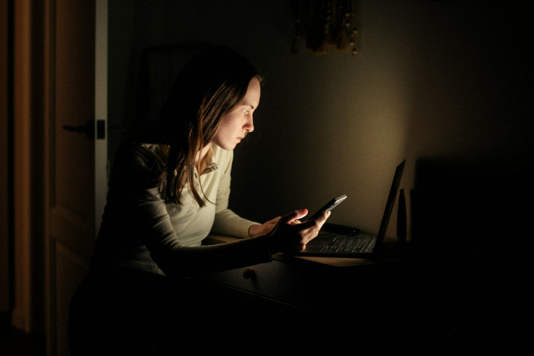 Woman looking at her phone late at night after a breakup, wondering whether her ex misses her.