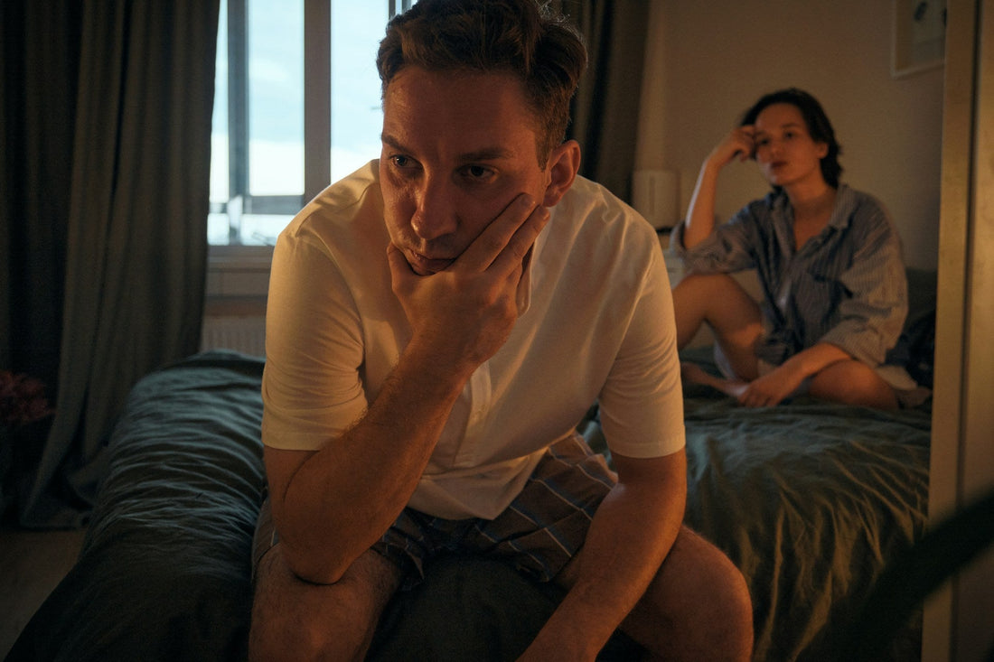 Man sitting apart from his partner during a tense conversation about relationship boundaries and consequences
