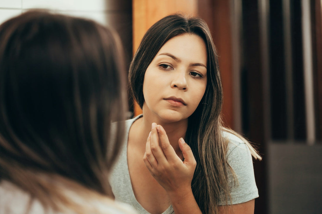 Woman looking at herself in a mirror while comparing her appearance after discovering her boyfriend cheated
