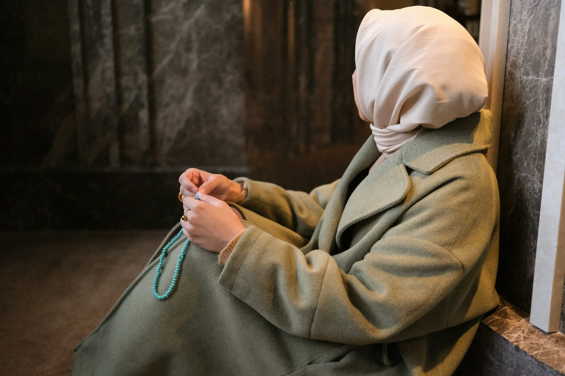 Muslim woman sitting alone with prayer beads while maintaining no contact and healing after ending a relationship.
