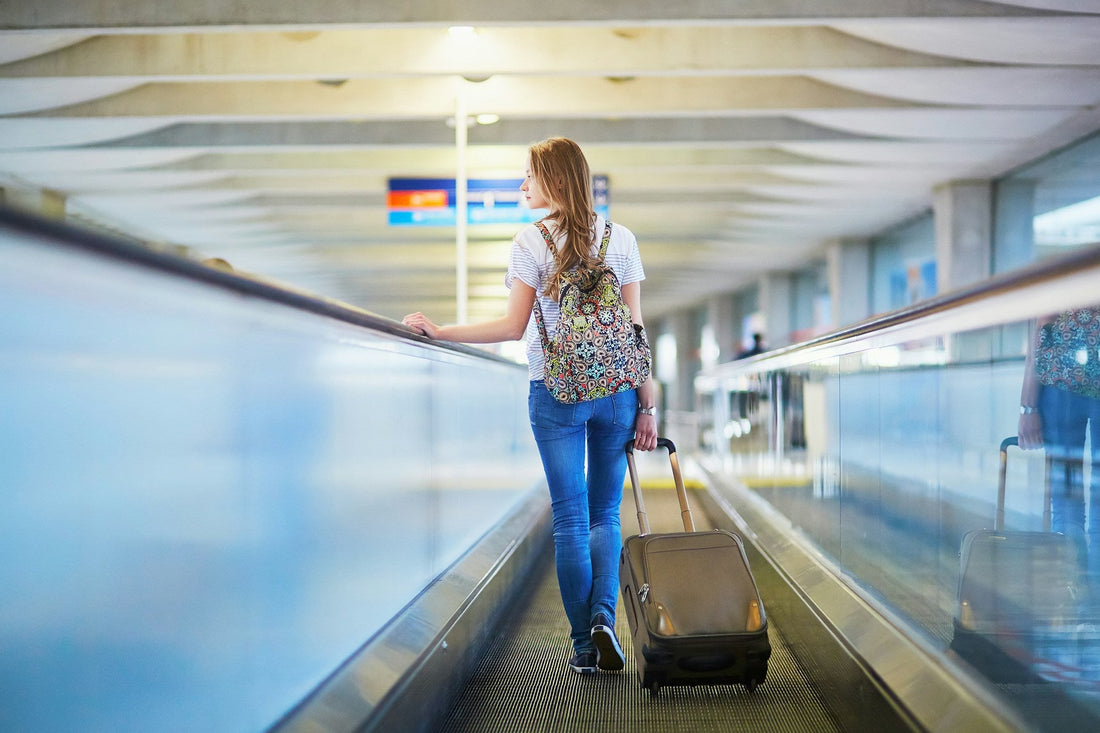 tourist girl with backpack and carry on luggage in international airport on a solo trip after a breakup