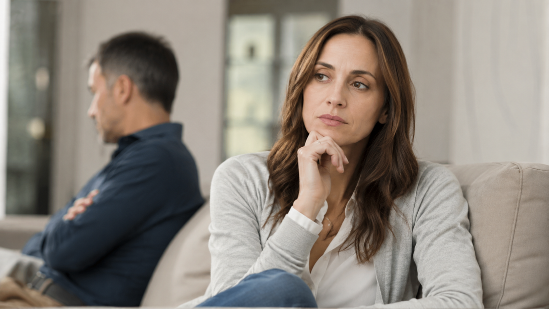 Woman reflecting on her marriage while her husband sits blurred in the background.