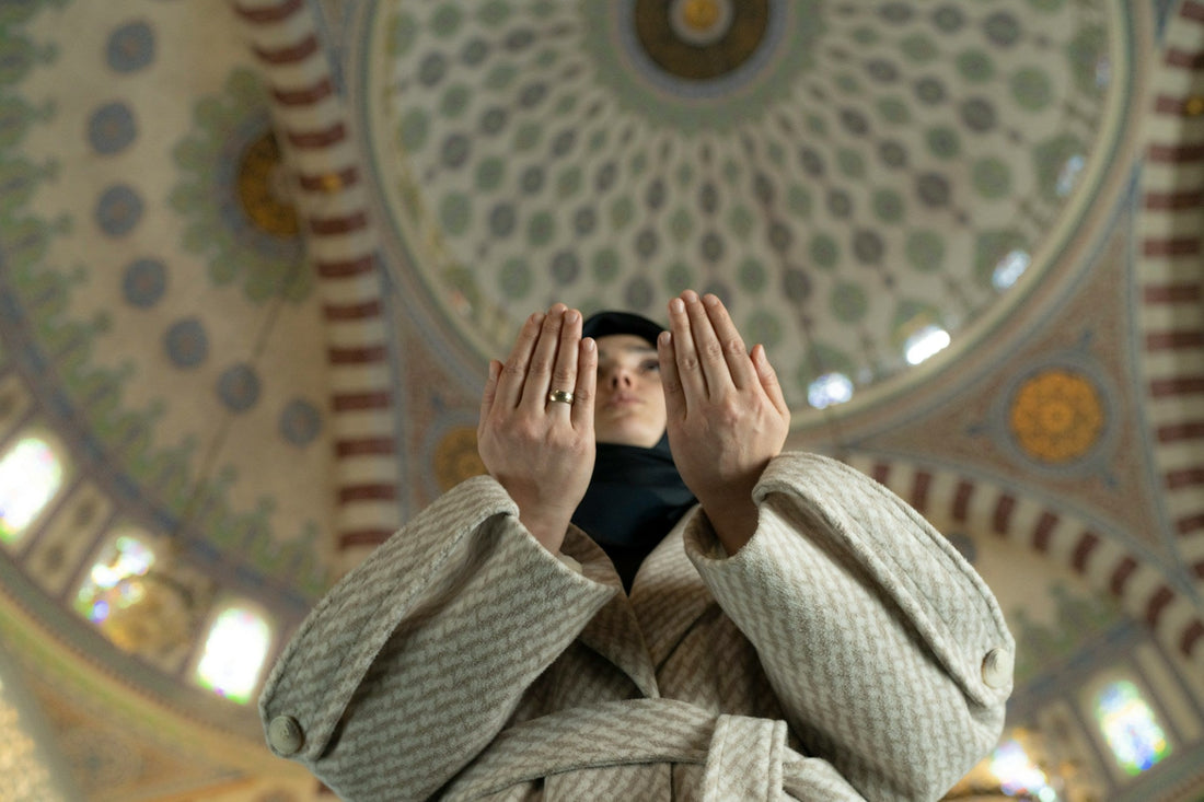 Muslim woman raising her hands in prayer inside a mosque while seeking guidance about relationship red flags after istikhara.