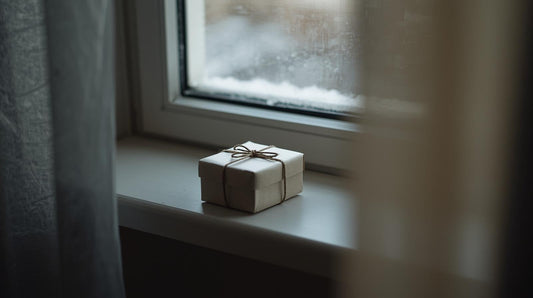 Minimal wrapped Christmas gift box on windowsill in soft winter light symbolizing long distance holiday connection