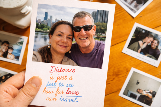 Real couple photo styled as a polaroid on a wooden desk with the quote "Distance is just a test to see how far love can travel" representing long distance relationship date ideas and emotional connection