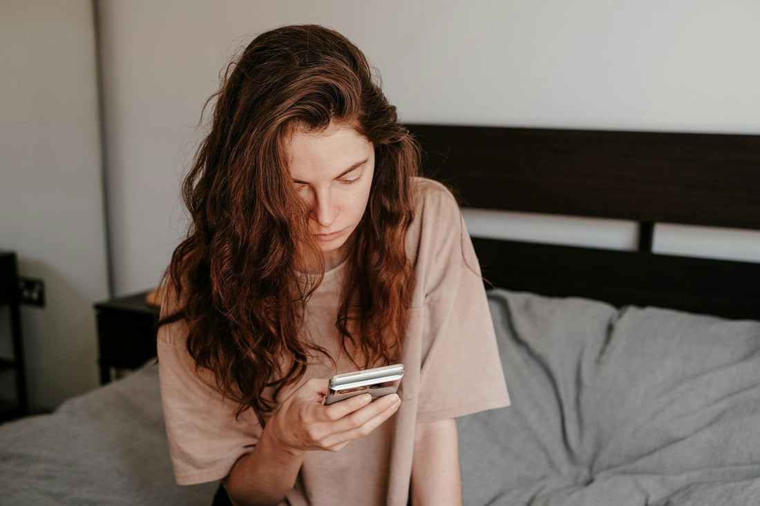 Woman looking sadly at her phone as a long-distance partner becomes emotionally distant