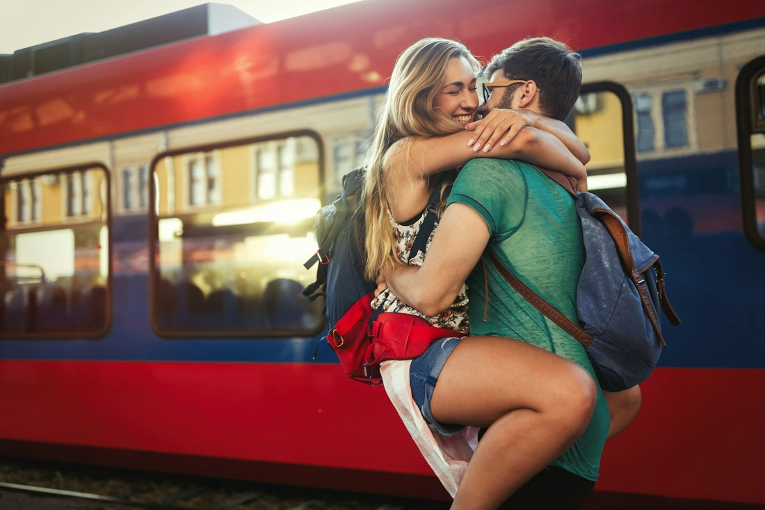 Couple embracing at a train station after time apart in a long-distance relationship.