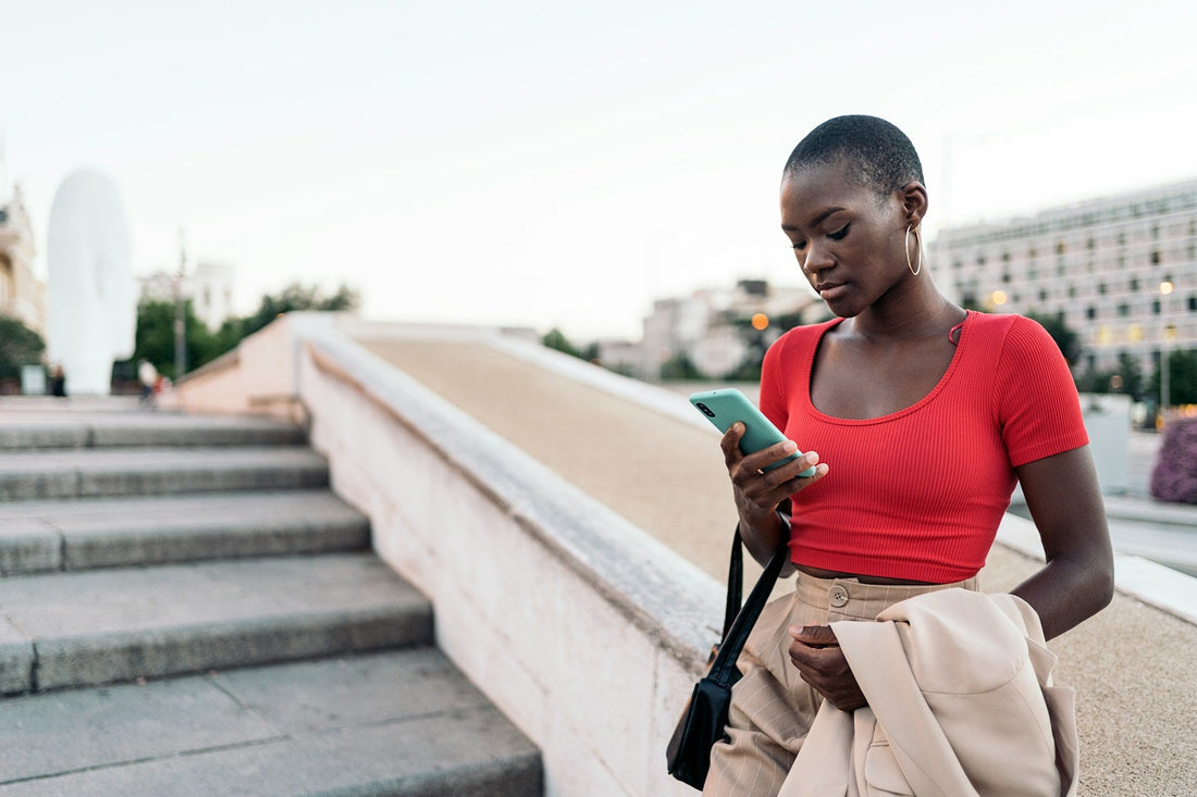 Woman looking at her phone outdoors, symbolising uncertainty about the future of a long-distance relationship without a clear end date.