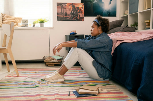 Woman sitting alone on the floor beside her bed, looking emotionally withdrawn and tired, representing low libido in women and reduced sexual desire.