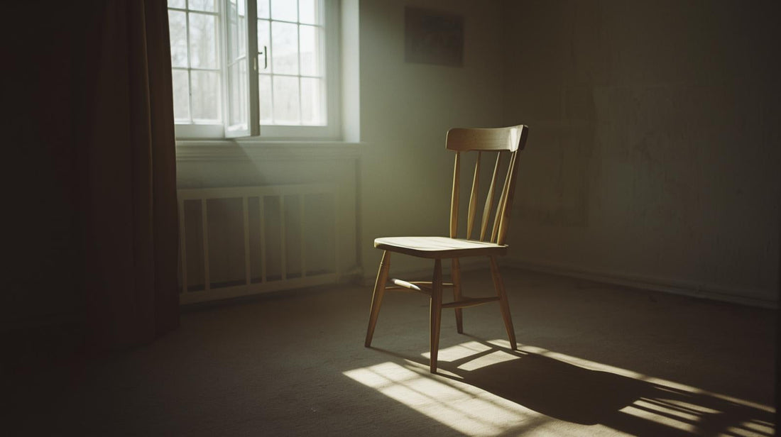Wooden chair in a quiet room lit by soft window light, casting long shadows across the floor