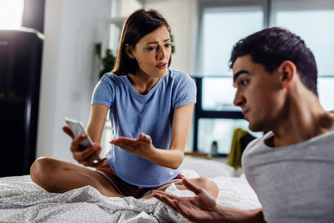 Woman confronting her boyfriend with a phone after suspecting he is cheating in their relationship