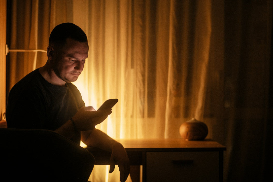 Man sitting alone at night looking at his phone after discovering his girlfriend of 10 years married someone else.