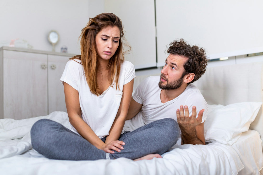 Man sitting thoughtfully beside his partner while questioning whether low libido is physical or relationship-related