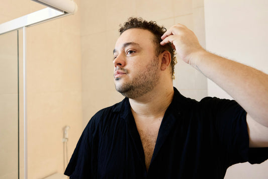 Man checking thinning hair and visible scalp before applying a hair concealer