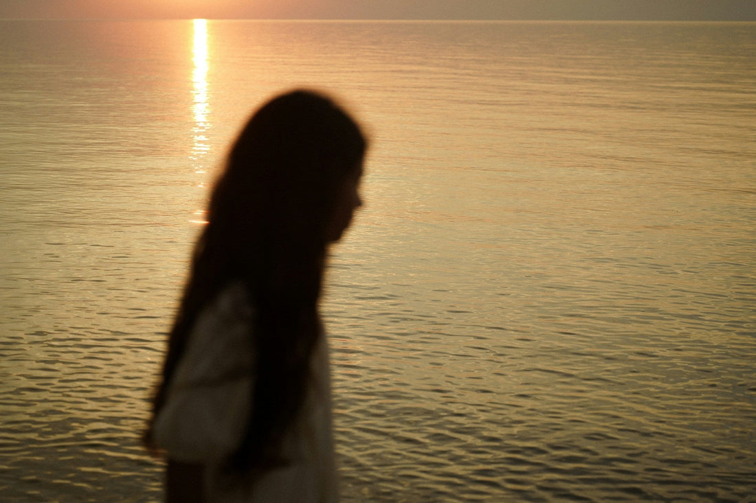 blurred figure by the water at sunset representing still not being over an ex after a breakup